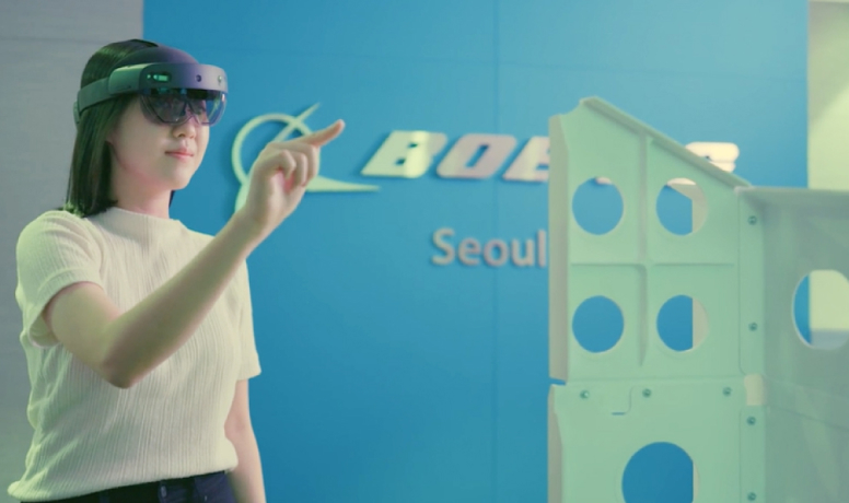 Student using augmented reality in front of a Boeing sign, exploring innovative aerospace solutions.
