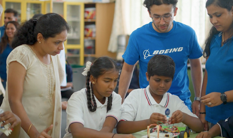 Students and Boeing volunteers collaborate on a STEM project in a school, promoting education and innovation in India.